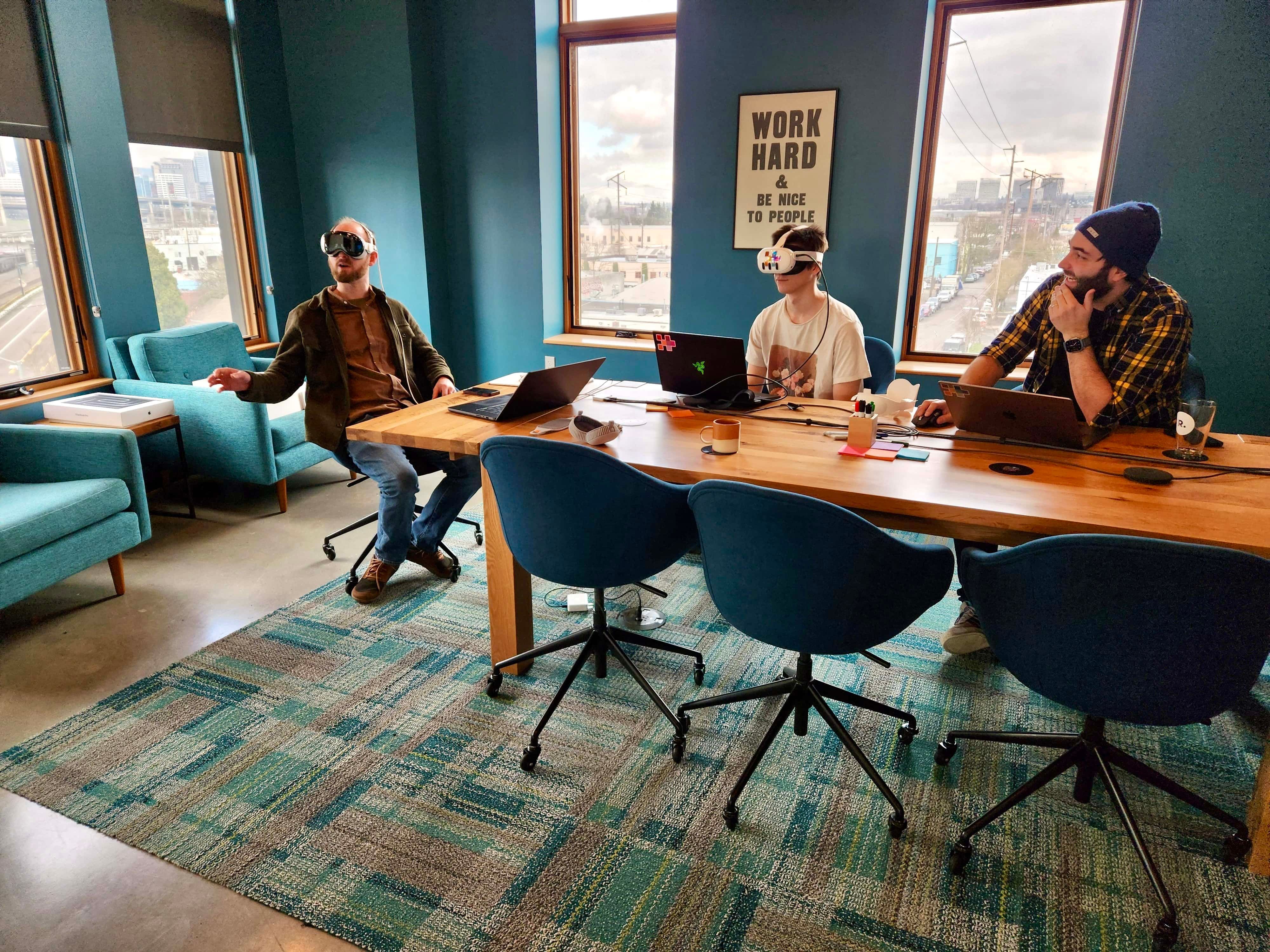 3 People working in an office, wearing different VR headsets (Oculus Quest, Apple Vision Pro)