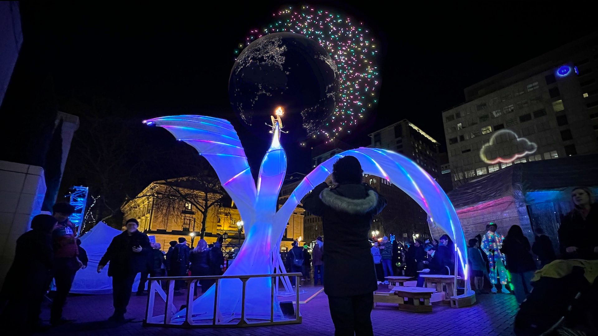 An illuminated art sculpture with a digital glove above it.