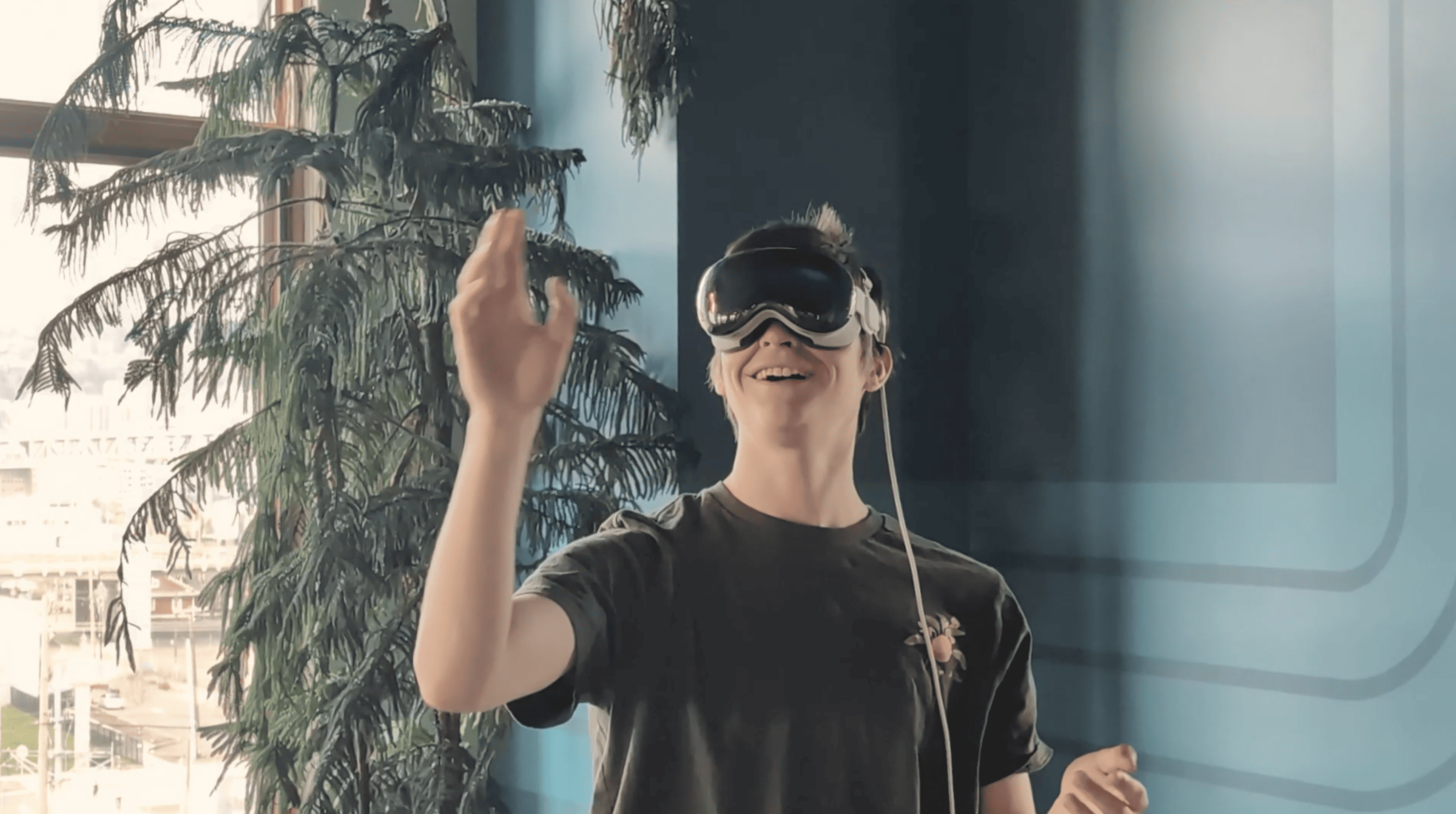 A person wearing an Apple Vision Pro. They are smiling and gesturing as if playing with bubbles.